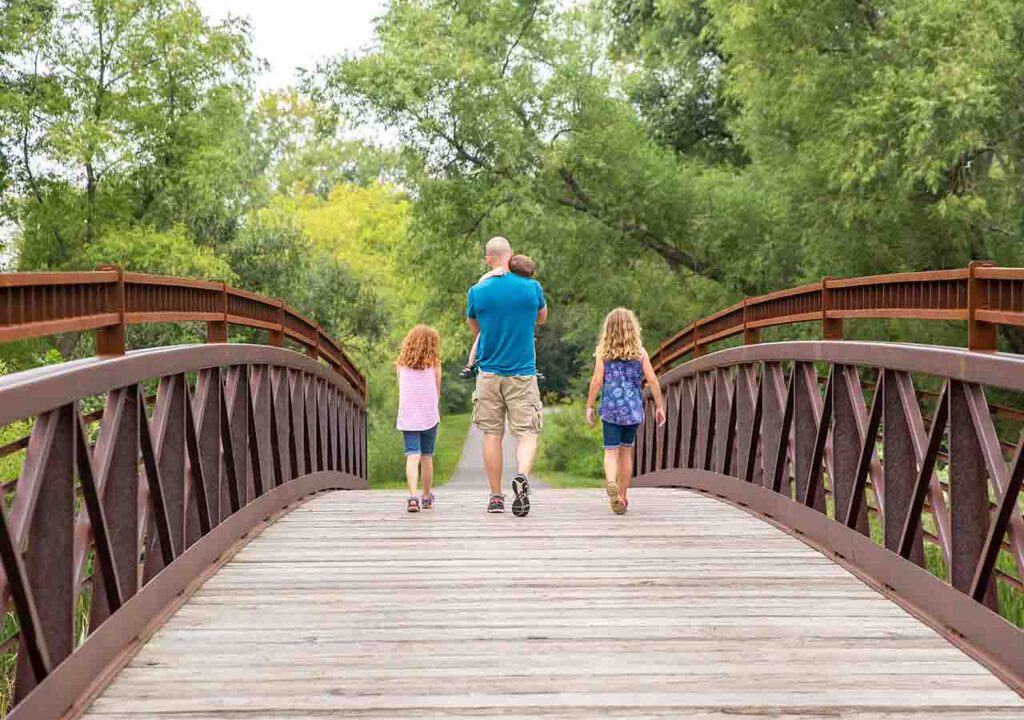 BridgeWay Pediatrics: Dad walking across a bridge with children